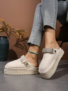 Gros plan de mules à plateforme beiges, texture daim et boucle métallique.