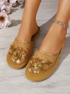 Detailansicht von goldenen Netzhausschuhen mit Paillettenblumen an den Modellfüßen
