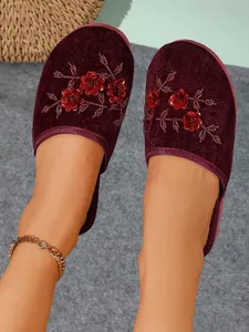 Dettaglio ravvicinato di pantofole in velluto bordeaux con ricamo floreale 3D e paillettes