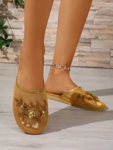 Detail von goldenen Netz-Slippern mit aufwendiger Blumenstickerei und Pailletten.