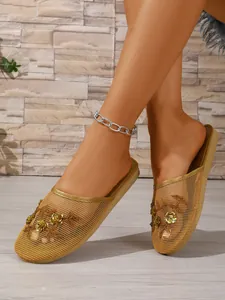 Detail goldene Mesh-Pantoletten mit zarter Blumenstickerei und Paillettenverzierung.