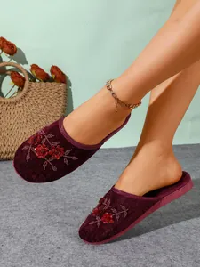 Primo piano di pantofole in velluto bordeaux con intricati ricami floreali in paillettes