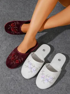 Vista dettagliata di eleganti pantofole in velluto con ricamo floreale di paillettes.
