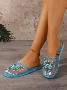 Close-up of elegant blue mesh mule slippers with delicate flower embroidery and beadwork