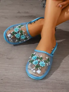Detail of blue mesh mules with intricate floral embroidery and sparkling beadwork