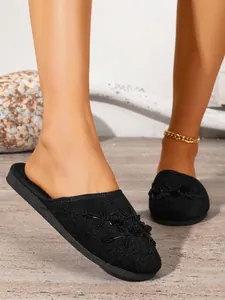 Primo piano di eleganti pantofole nere chiuse con intricati ricami floreali decorativi