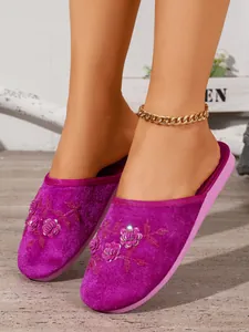 Primo piano di pantofole in velluto viola con ricami floreali e dettagli in paillettes