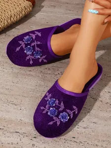 Dettaglio ravvicinato delle pantofole in velluto viola con ricami e paillettes.