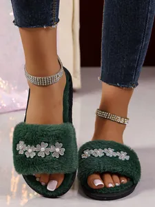 Dettaglio di pantofole in peluche verde scuro con fiori di diamanti scintillanti e perle