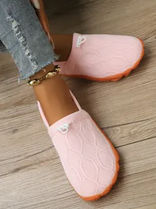 Detailansicht der rosa atmungsaktiven Strick-Barfußschuhe für Damen auf Holzboden
