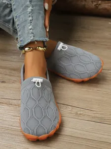 Nahaufnahme grauer Strick-Barfußschuhe mit rutschfesten orangefarbenen Gummisohlen