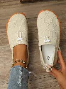 Nahaufnahme von beigen Barfuß-Sneakern für Damen mit Strickmuster und orangefarbener Sohle