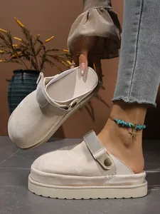 Détail de sabots beige à plateforme avec finition suédée et bride ajustable.