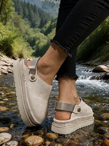 Sabots beige à plateforme avec bride réglable portés à l'extérieur près d'une rivière