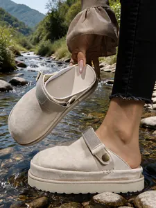 Gros plan détaillé de sabots à plateforme beiges dans un décor naturel de ruisseau.