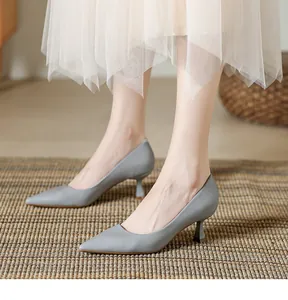 Gros plan d'escarpins gris à talons hauts portés avec une jupe en tulle sur un tapis