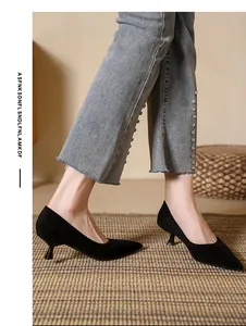 Elegant black suede pointed-toe kitten heel pumps shown on a model wearing denim jeans