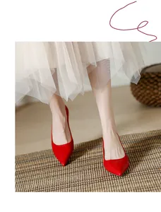 Gros plan d'élégants escarpins rouges à bout pointu portés avec une jupe en tulle.