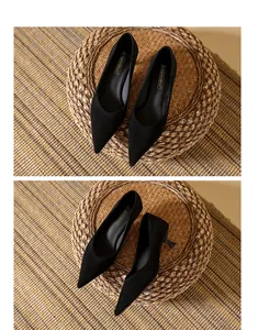 Detailed macro view of black suede pointed-toe kitten heel pumps on a rustic woven mat