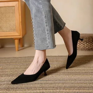 Elegant black suede pointed-toe pumps with kitten heels shown in a cozy home setting