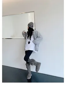 Woman in grey tall platform snow boots with warm fur lining in a modern minimalist setting