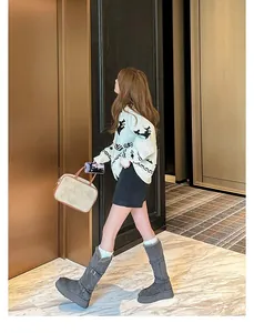 Model wearing stylish grey tall snow boots with thick platform soles and buckle.