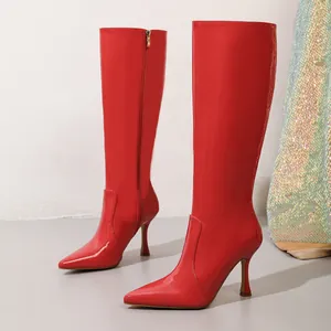 Detailed view of vibrant red patent leather stiletto boots with elegant pointed toe