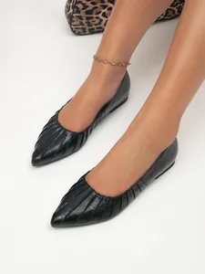 Vue détaillée de chaussures plates noires plissées à bout pointu portées par un mannequin