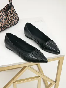 Gros plan sur des ballerines noires à bout pointu avec détails plissés chic.