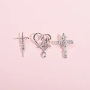 Macro view of silver Amazing Grace and faith cross brooch pins set on pink background