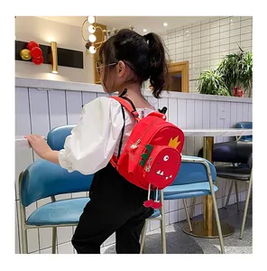 Vista detallada de una mochila de dinosaurio roja usada por una niña en un café.