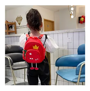 Vista trasera de un niño con mochila roja de dinosaurio animado en un café