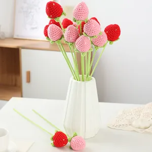 Detailansicht von handgehäkelten Erdbeeren in einer weißen Vase als gemütliche Deko.