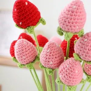 Makro-Detailansicht von handgestrickten roten und rosa Häkelerdbeeren für die Dekoration.