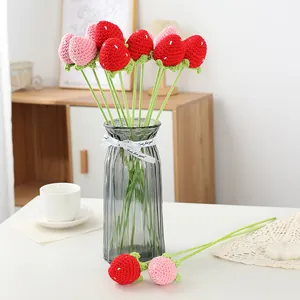 Detailansicht handgefertigter, gehäkelter Erdbeerblumen in einer eleganten Glasvase