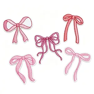 Close-up detail of five assorted pink embroidered bow patches for clothing and DIY decor.