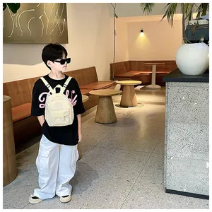 Sac à dos stylé blanc crème pour enfants porté par un garçon dans un café chic