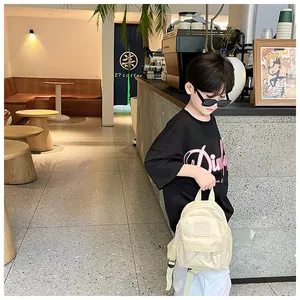 Mini sac à dos beige élégant pour enfants dans un décor de café moderne et chic.