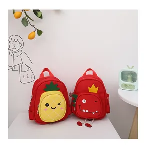 Vista detallada de mochilas rojas para niños con dibujos de piña y un dinosaurio.