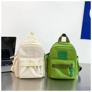 Détail montrant des mini sacs à dos verts et crème pour enfants de maternelle près d'un laptop.