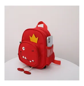 Vista lateral de una mochila roja de dinosaurio para niños con un teléfono en el bolsillo