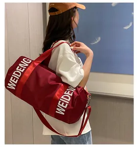 Dettaglio di una grande borsa sportiva bordeaux a cilindro portata da una modella