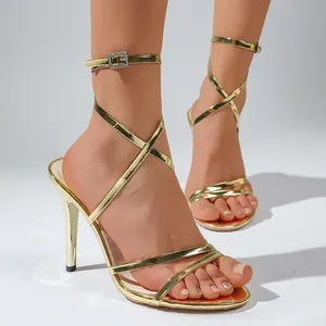 Close-up detail of elegant gold strappy high-heeled sandals with a sparkly crystal buckle