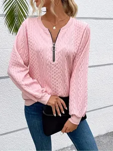 Detail of pink cable-knit sweatshirt with stylish circular ring half-zip neckline