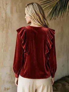 Elegant burgundy red velvet blouse featuring sophisticated back ruffle details and cuffed sleeves.