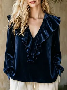 Elegant detail shot of a navy blue velvet blouse featuring a ruffled V-neckline