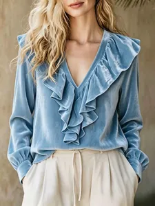 Detail view of a light blue velvet blouse featuring elegant V-neck and ruffle trim