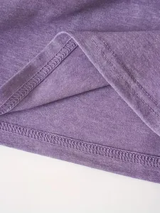 Detailopname van de zoom van een paars T-shirt met dubbel stiksel en stoftextuur.