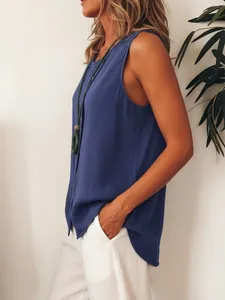 Side view detail of a loose blue sleeveless button-up shirt paired with white pants