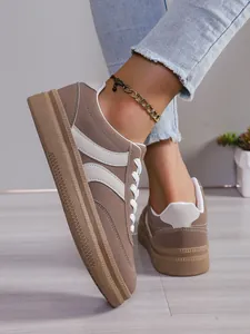 Gros plan de baskets compensées marron sur mannequin avec jean et bracelet